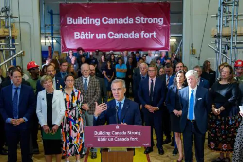Le premier ministre du Canada, Mark Carney, livre un discours entouré d'une foule avec une grande banderole déployée sur laquelle est inscrite le slogan " Bâtir un Canada fort".