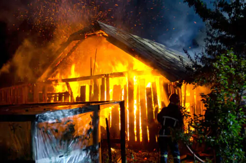 Wooden house or barn burning on fire at night.