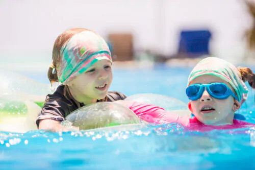 Deux petites filles jouent dans une piscine par une journée ensoleillée.