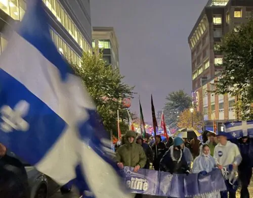 Des militants indépendantistes marchent dans une rue du centre-ville de Gatineau en brandissant des drapeaux du Québec.