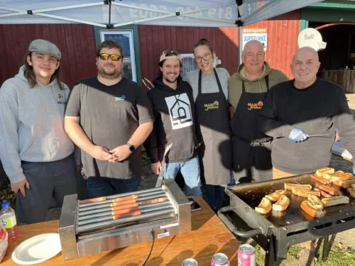 Un groupe d'employés de la Maison des jeunes de Maniwaki prend la pause près d'un barbecue sur lequel cuisent des hot-dog.
