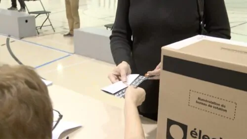 Une personne reçoit son bulletin de vote dans un bureau de scrutin.