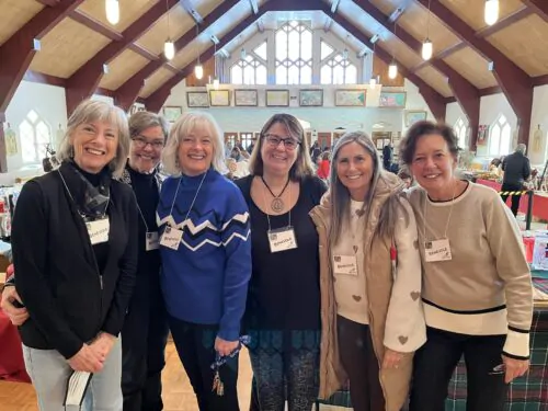 Un groupe de femme regroupé pour prendre une photo à l'occasion d'une foire du temps des Fêtes dans une église.