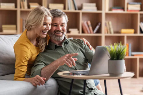 Digital Entertainment. Cheerful Middle Aged Couple Using Laptop At Home Together