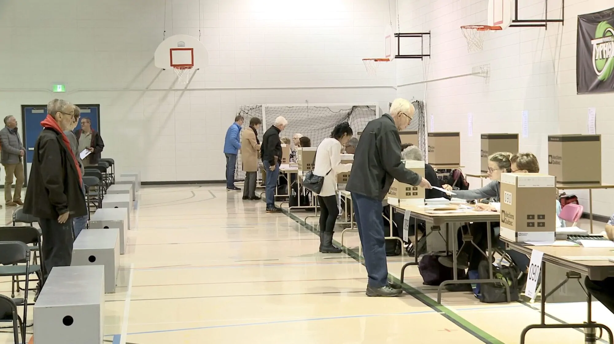 Des personnes votent dans un gymnase transformé en bureau de vote.