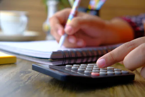 Gros plan sur la main d'une personne en train de se servir d'une calculatrice.