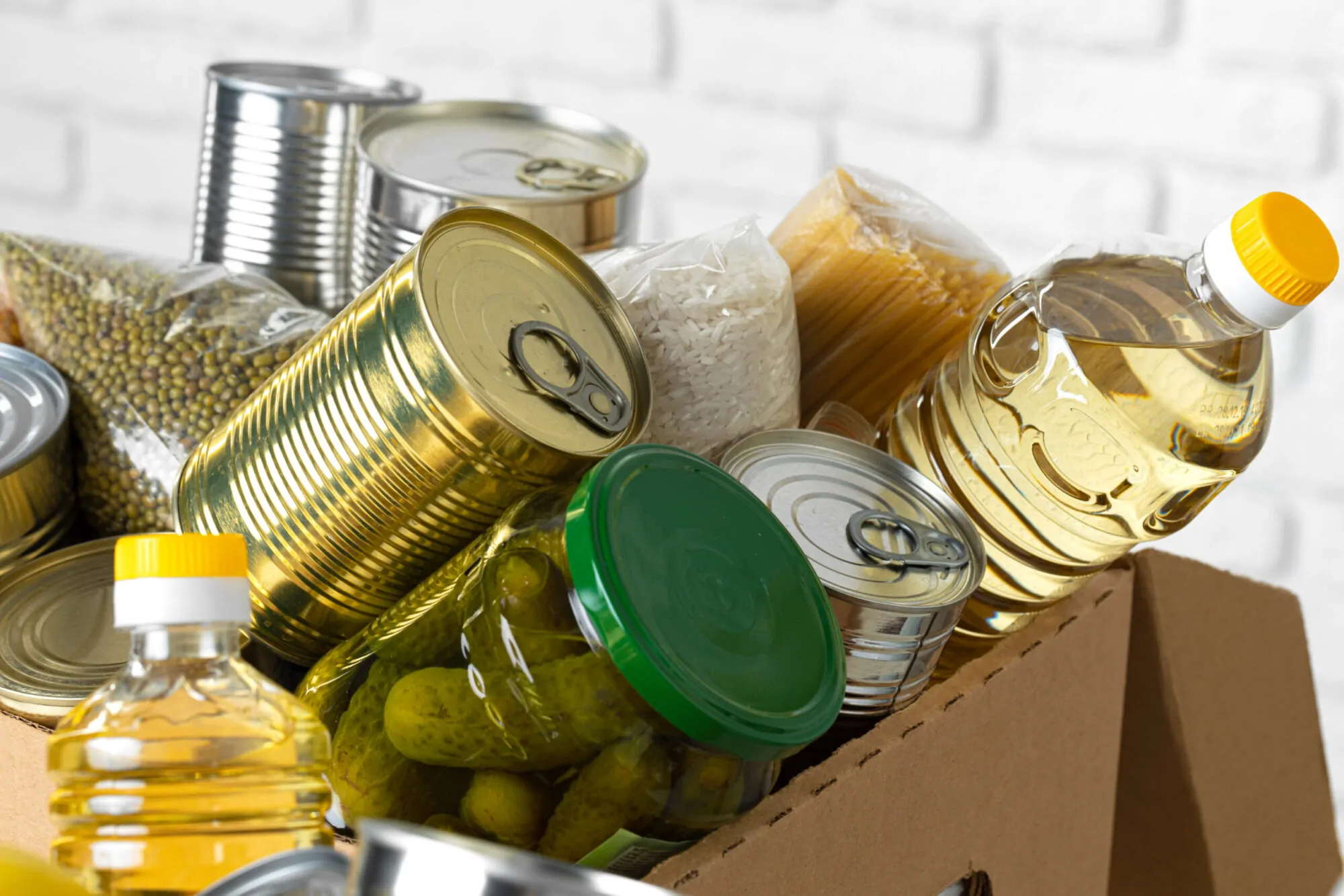 Un carton rempli de boîtes de conserve, de riz et de pâtes.