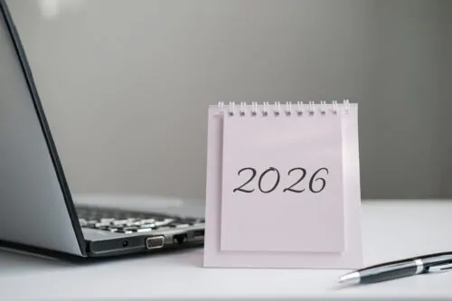 Calendar displaying "2026" is featured on desk next to laptop and pen. Great for themes of business, technology, and professional planning for the upcoming year